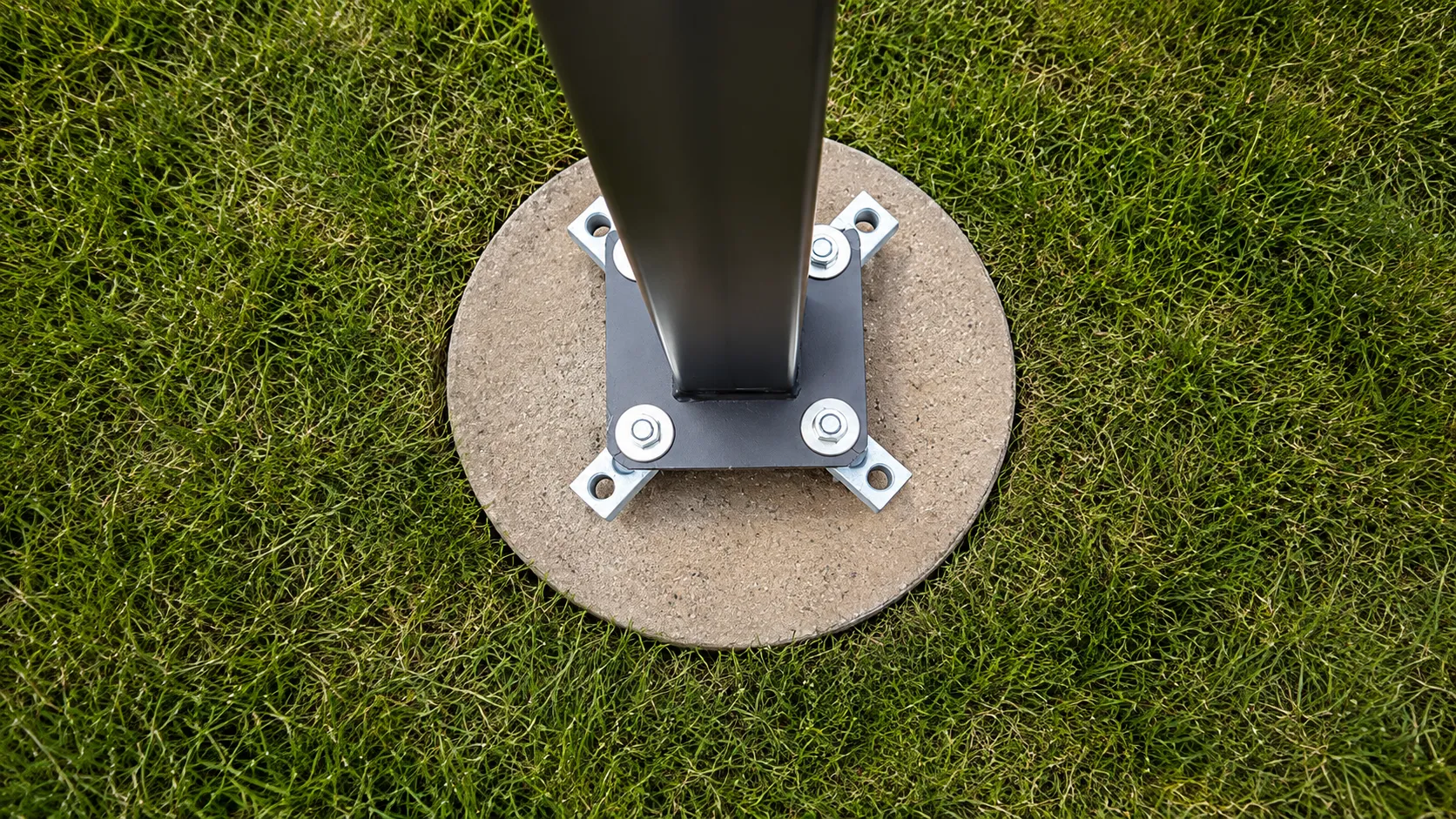 Light pole base with anchor bolt adapter installed on a concrete footing