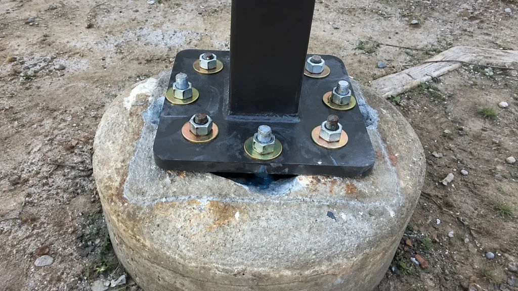 Light pole base plate secured with anchor bolts on an existing concrete footing