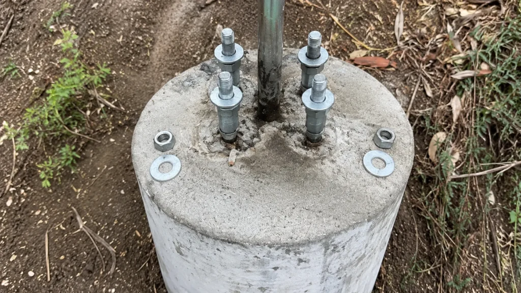 Light pole anchor bolts with leveling nuts and washers installed on a concrete footing