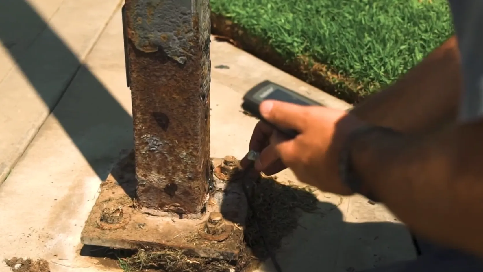 Corroded light pole base showing rust, coating damage, and structural deterioration