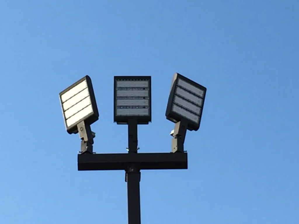 Three LED light fixtures mounted on a light pole bullhorn